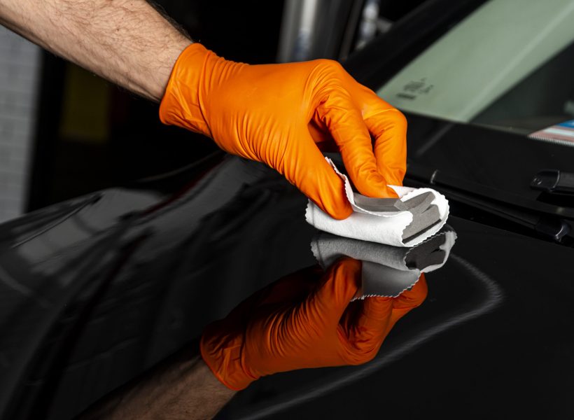 Car polish wax worker hands polishing car. Buffing and polishing vehicle with ceramic. Car detailing. Man holds a polisher in the hand and polishes the car with nano ceramic. Tools for polishing