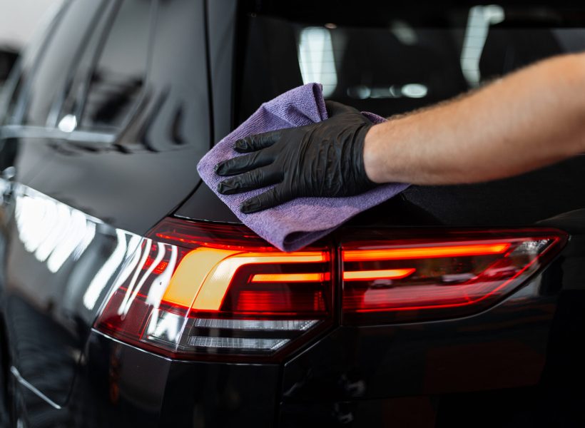 Professional man washes car and wipes with microfiber. Detailing and car wash